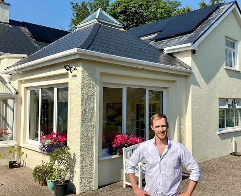Scott McKechnie outside a home with rooftop solar panels
